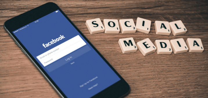 iPhone with the Facebook app open to the login in screen with the letters "Social Media" next to it