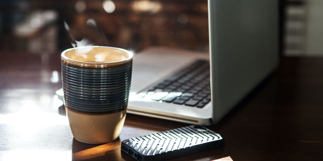 coffee mug by phone and laptop