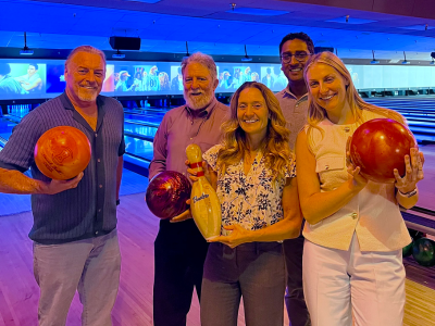 5 attendees posing with bowling balls in front of bowling lane